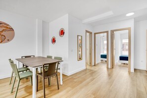 A modern interior with a dining table, chairs, and a hallway leading to a bedroom.