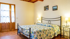 A bedroom with a bed, wooden door, two wall-mounted lamps, and a small table.