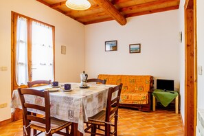 A dining area with a table, chairs, a sofa, and a television.