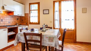 A kitchen with a dining table, chairs, and a window with curtains.
