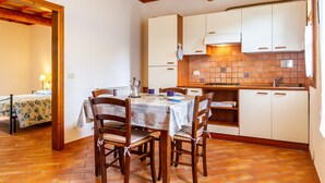 A kitchen with wooden cabinets, a tiled backsplash, and a dining table with chairs.