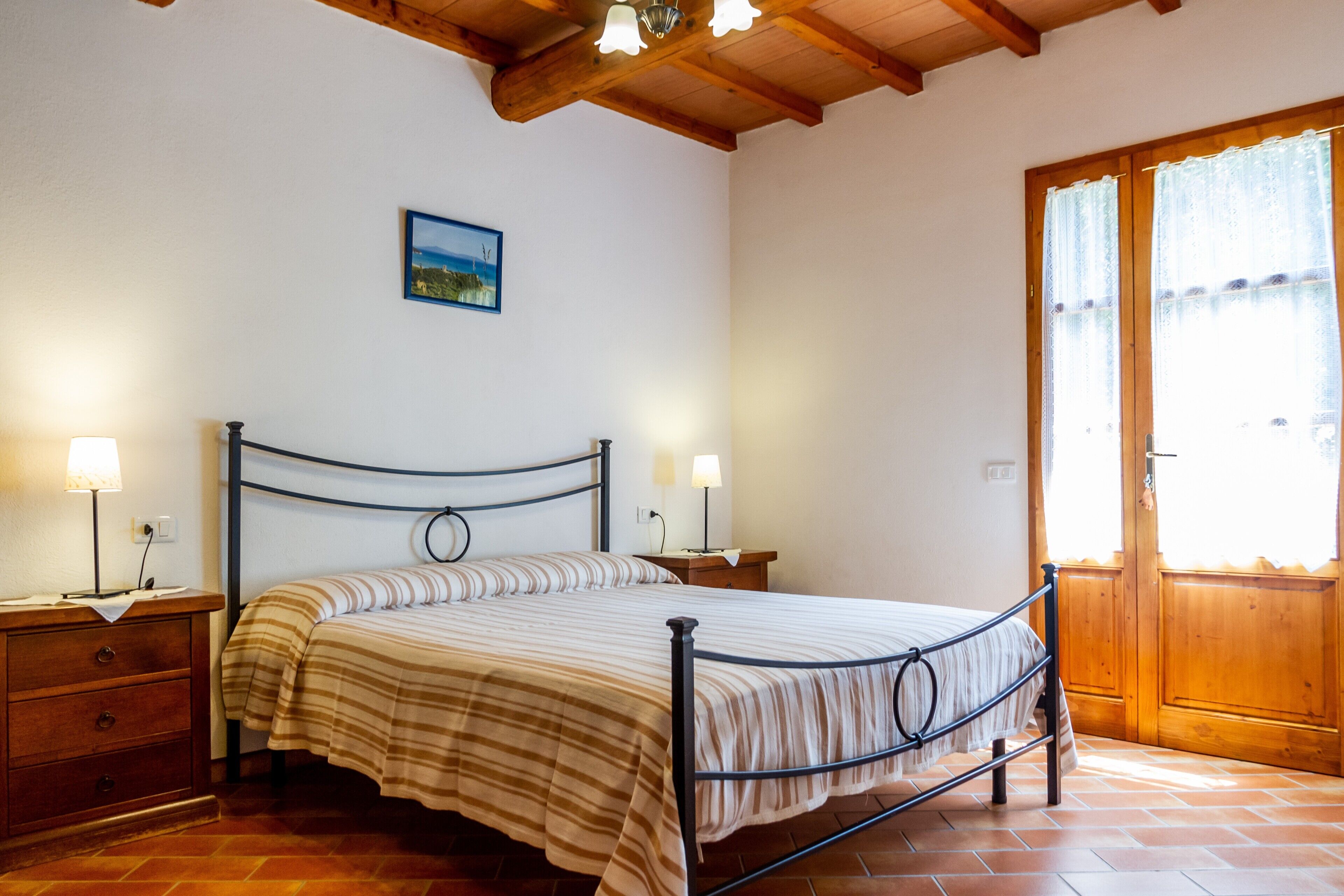 Ein Schlafzimmer mit Bett, Nachttischen, einer Holztür und einem Bild an der Wand.
