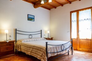 Une chambre à coucher avec un lit, des tables de chevet, une porte en bois et un tableau au mur.