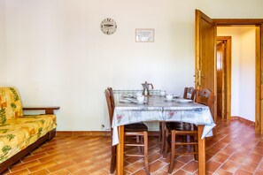 Un coin repas avec une table dressée pour quatre personnes, un canapé, une horloge et un certificat accroché au mur.