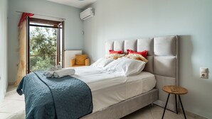 Un dormitorio con cama, ventana, una silla y una mesita.