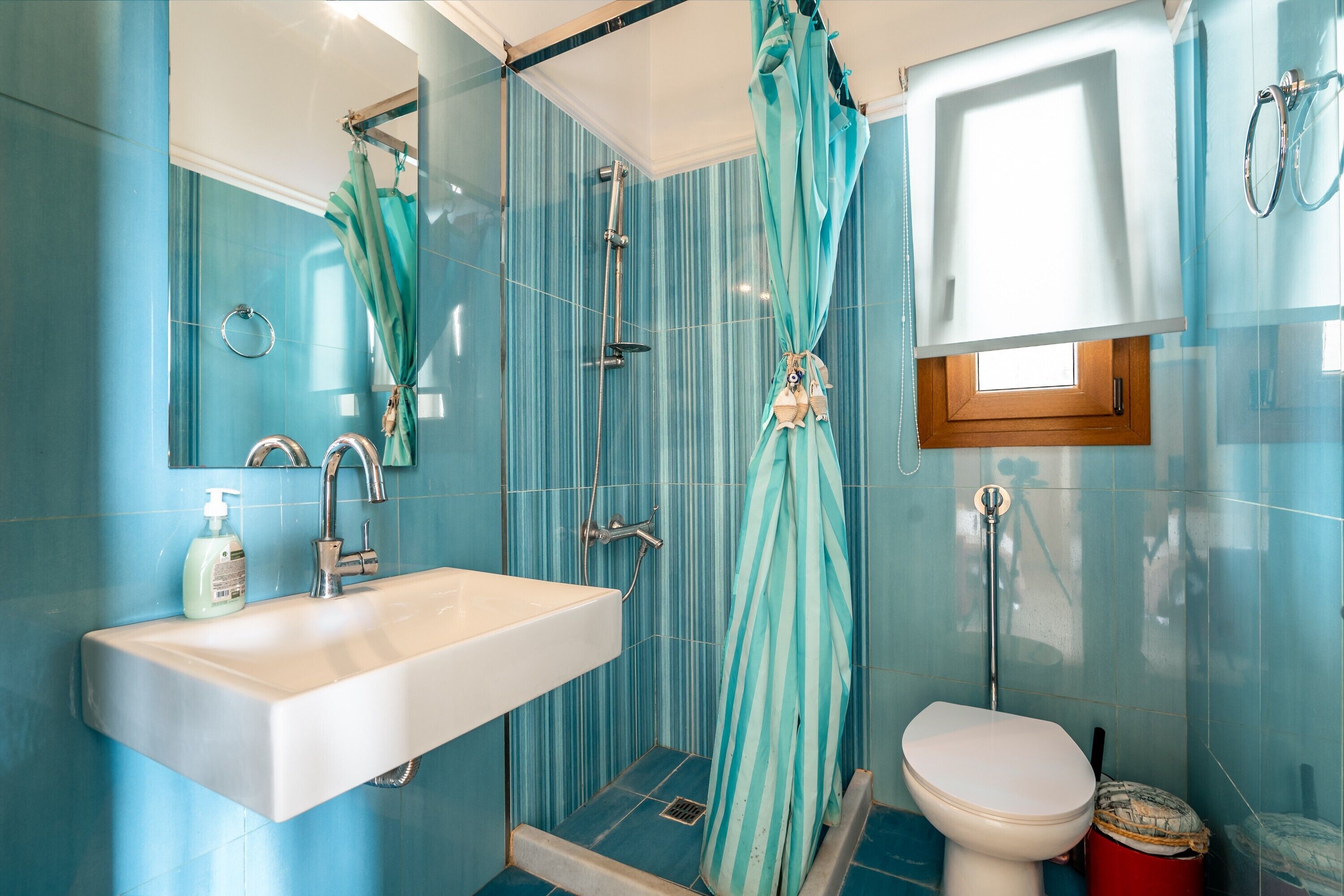 A bathroom with a shower, toilet, sink, and a window.