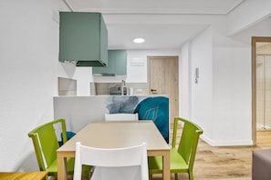 Una cocina compacta con electrodomésticos modernos, un comedor con mesa y sillas, y una puerta de madera.