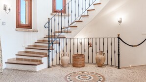 Un escalier avec une rampe en métal, un sol à motifs et deux vases sur le palier.