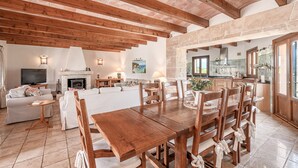 Un vaste espace de vie comprenant une table à manger en bois, des canapés et une cheminée.