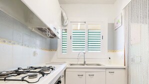 A compact kitchen with a gas stove, sink, and white cabinets. - 'Mirador Altafulla' 5th Floor with Two Terraces and Elevator (altafulla)