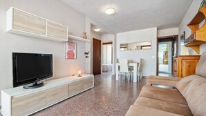 A modern living room with a flat-screen TV, a white entertainment unit, a beige sofa, and a dining area with a white table and chairs. - 'Mirador Altafulla' 5th Floor with Two Terraces and Elevator (altafulla)