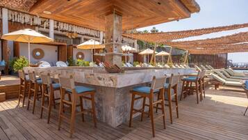 A wooden deck with a bar area, lounge chairs, and umbrellas.