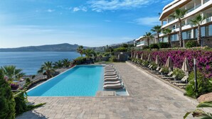 A pool with a clear view of the sea, surrounded by palm trees and lounge chairs. - Swissôtel Living Bodrum (Bodrum)