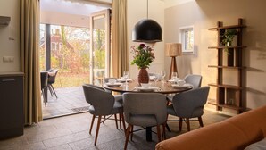 Un espace repas moderne avec une table ronde, des chaises grises et un luminaire suspendu noir.