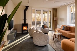 Ein modernes Wohnzimmer mit Kamin, bequemen Sitzmöglichkeiten und einem Fernseher.
