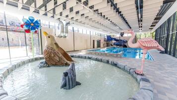 An indoor swimming pool with a dolphin sculpture, a flamingo sculpture, and a bird sculpture.
