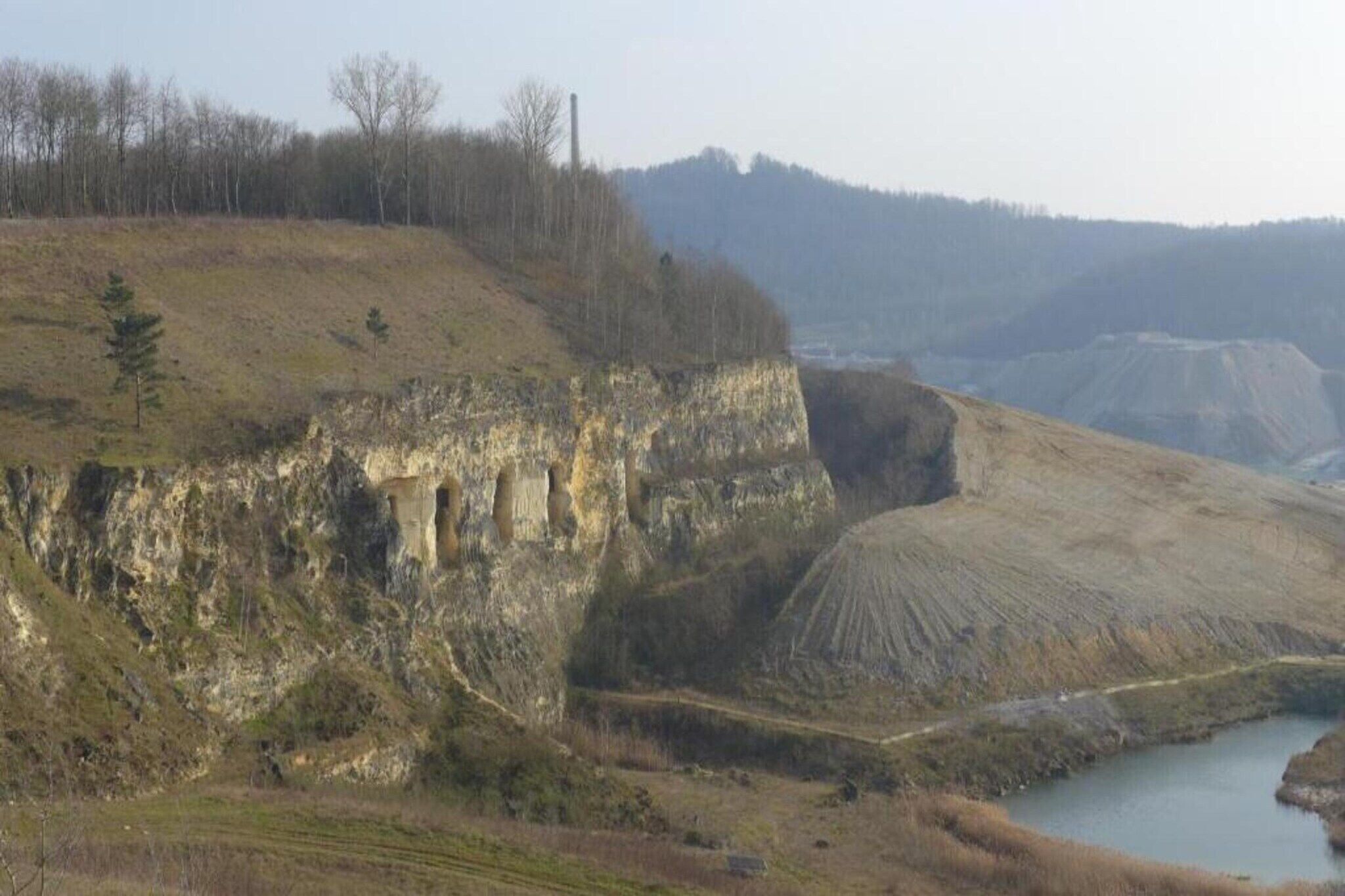 A landscape with a cliff, a river, and distant hills.