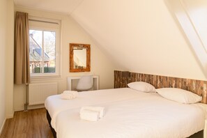 Een slaapkamer met een groot bed, een raam met gordijnen, een spiegel en een radiator.