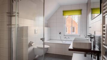 Een moderne badkamer met een douchecabine van glas, een wit toilet, een badkuip en een wastafelmeubel met een wastafel.