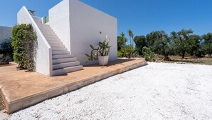 Un edificio moderno con fachada blanca, una escalera y una planta de cactus.