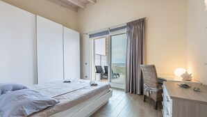Een slaapkamer met een bed, een bureau, een stoel en uitzicht op buiten.