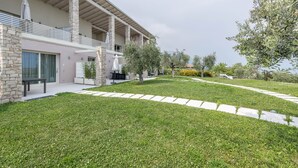 Een modern huis met een gevel van natuursteen, een overdekte patio en een verzorgd gazon.