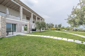 Une maison moderne avec une façade en pierre, un patio couvert et une pelouse bien entretenue.