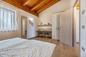 Un dormitorio con cama, escritorio, dos sillas, armario y espejo.