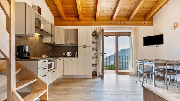 Una cocina moderna con armarios de madera, una máquina de café y un comedor con mesa y sillas.