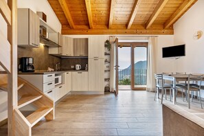 Une cuisine moderne avec des meubles en bois, une machine à café et un coin repas comprenant une table et des chaises.