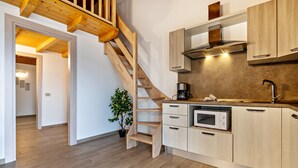 Una cocina moderna con armarios de madera, un microondas empotrado y una escalera.