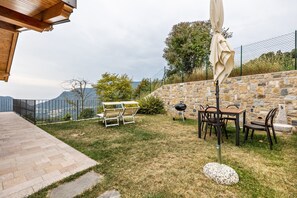 Eine Terrasse mit Gartenmöbeln, einem Grill und einer Steinmauer.