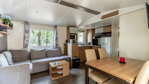 A compact RV interior with a sofa, dining table, and kitchenette. - Mobile Home for 6 Guests with Shared Pool and Private Terrace (Saint-Brevin-les-Pins)