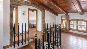 A spacious room with a wooden ceiling, a staircase with ornate black and gold railings, and a view through an arched doorway. - Villa 'Casa Al Mare' with Private Terrace, Wi-Fi and Air Conditioning (Siracusa)
