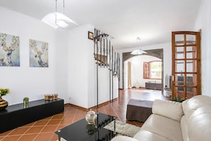 Un vaste espace de vie comprenant une table basse noire, un canapé blanc et un escalier menant à un niveau supérieur.