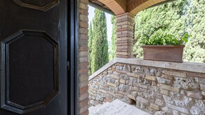 Een stenen muur met een bloempot, een donkere deur en een boogvormige bakstenen constructie.
