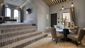 Een modern interieur met stenen treden, een eethoek met patroonstoelen en een aan de muur bevestigde televisie.