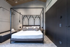 A modern bedroom with a four-poster bed, a small bedside table, and a bench.