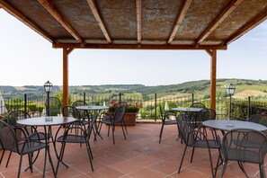 A terrace with outdoor seating, a pergola, and a scenic view of rolling hills.