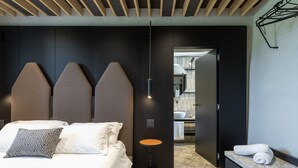 Une chambre d’hôtel moderne, équipée d’un lit, d’une petite table ronde et d’une banquette intégrée avec des serviettes.