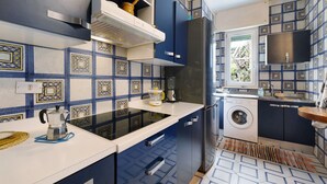 A compact kitchen with a washing machine, a stove, and a microwave. - Apartment 'Il Giardino Di Giò' with Mountain View, Private Terrace and Wi-Fi (Finale Ligure)