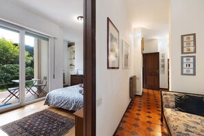 Une chambre à coucher comprenant un lit, un canapé, un tapis à motifs et donnant sur un jardin grâce à une porte coulissante.