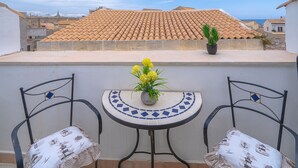 A terrace with a tiled roof, two chairs, a small table, and a potted plant. - Holiday Apartment 'Cheyenne's House' with Terrace, Balcony & Wi-Fi (Siracusa)