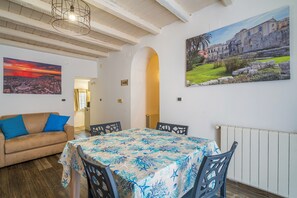 Un comedor con una mesa dispuesta para cuatro personas, un sofá y dos cuadros en las paredes.