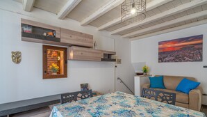 A room with a bed, a sofa, a dining table, and a cityscape painting. - Holiday Apartment 'Cheyenne's House' with Terrace, Balcony & Wi-Fi (Siracusa)