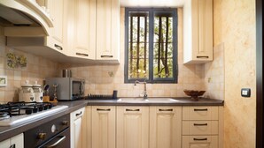Eine Küche mit Gasherd, Backofen, Mikrowelle und einem Fenster mit Gitter.