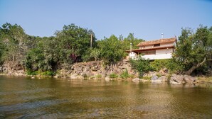 Ein Haus am Fluss mit felsigem Ufer und Bäumen.