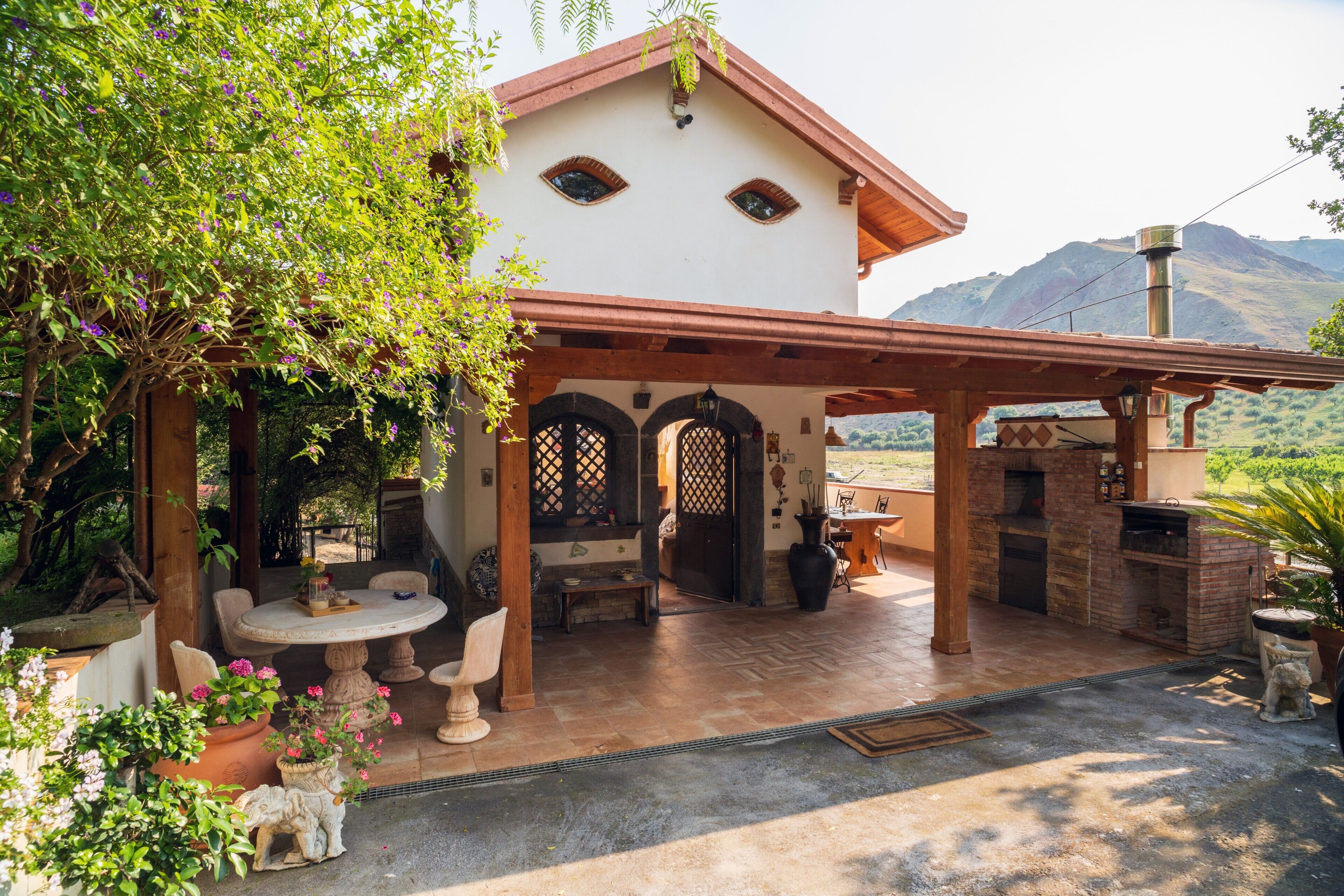 A covered patio with a table and chairs, a brick fireplace, and a view of the mountains.