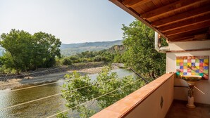 Ein Balkon mit Blick auf einen Fluss, Bäume und eine Berglandschaft.