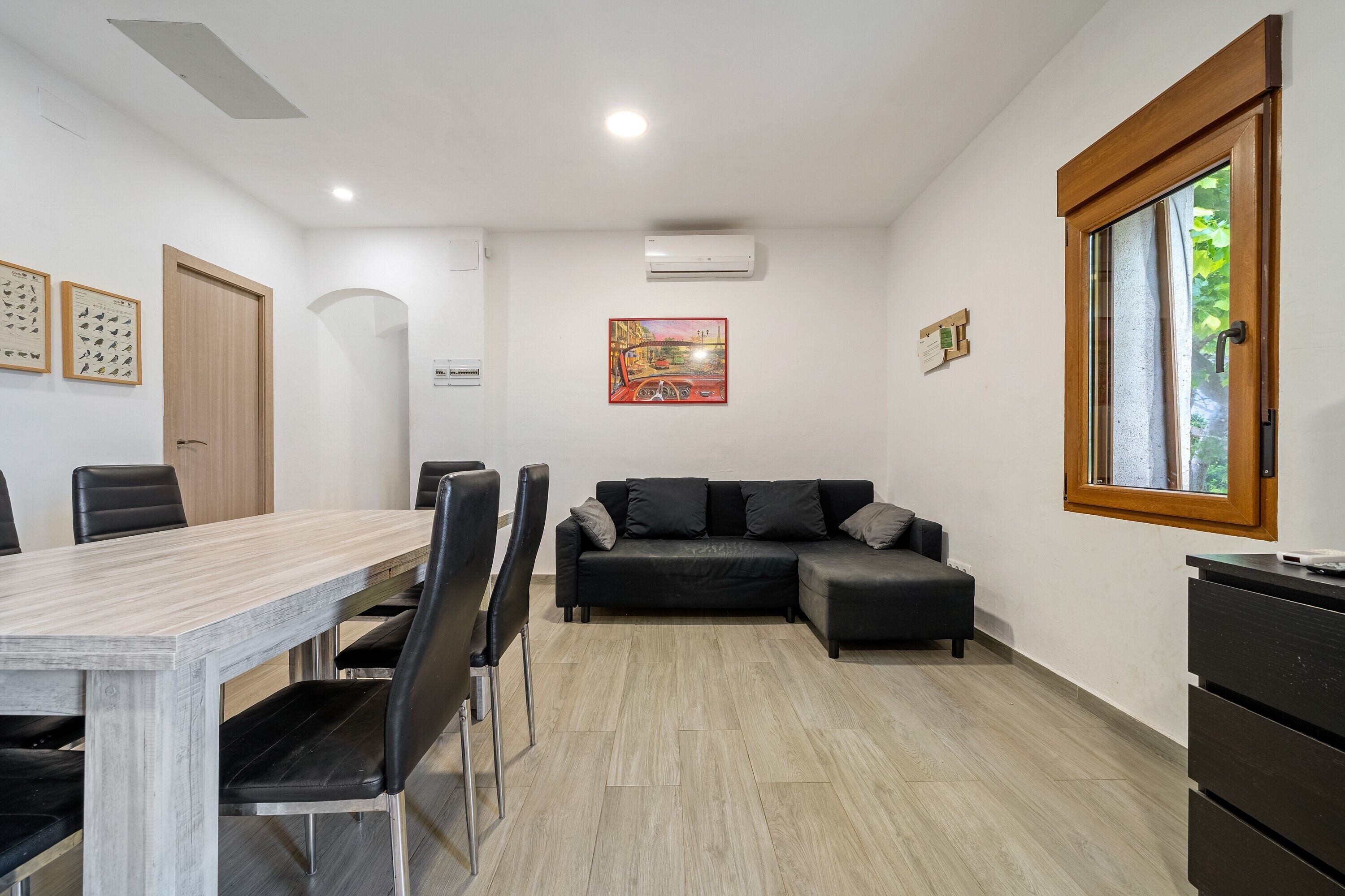Una habitación moderna con una mesa de comedor, sillas, un sofá y un ventanal.